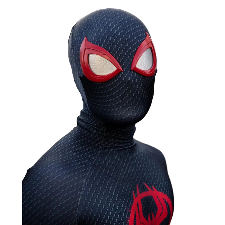 Person wearing a black superhero costume with red accents in front of a metal gate.